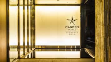 A hotel entrance with a modern design, featuring a star logo and the name "CANDEO HOTELS" on the wall.