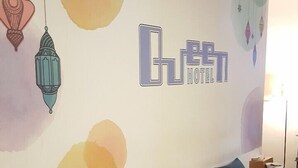 A hotel reception area with a seating area, a wall with a logo, and decorative elements. - Hotel Queen (Taipei)