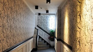A hallway with patterned wallpaper, a dark wooden floor, and a staircase with a railing. - Hotel Queen (Taipei)