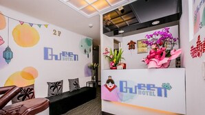 A hotel reception area with a modern design, including a reception desk, a seating area with a sofa and chairs, and decorative wall art. - Hotel Queen (Taipei)