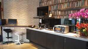 Ett modernt kök med en tegelvägg, en bokhylla, en platt-TV, en brödrost och en orkidé i en kruka.