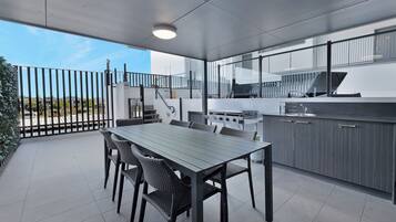Un espacio cocina al aire libre con mesa y sillas, una parrilla y vistas del paisaje circundante.