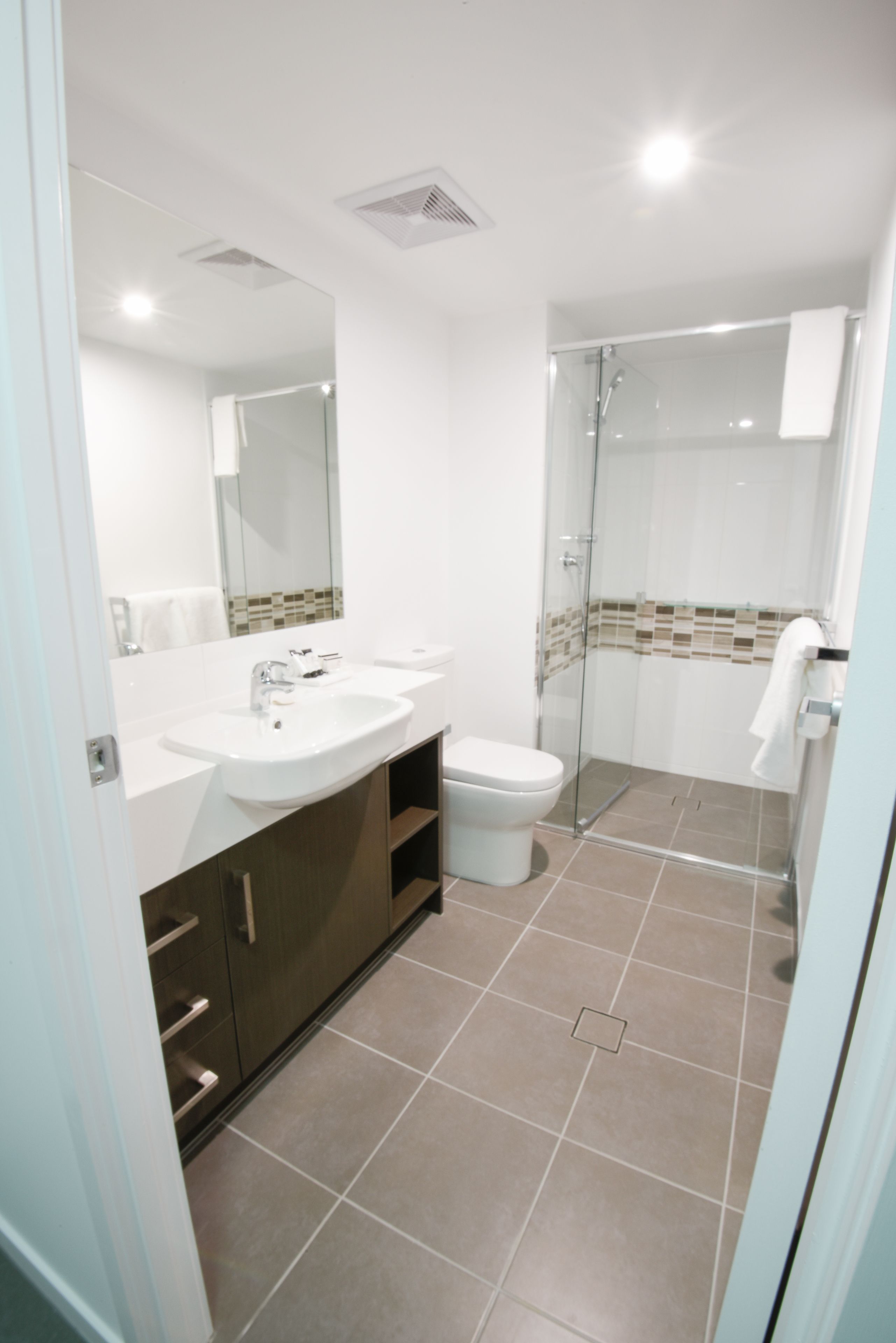 Ein modernes Badezimmer mit Waschbecken, Toilette und Duschkabine aus Glas.