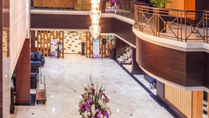 Eine großzügige Lobby mit einer zentralen Blumenkomposition, einem Chandelier und einer modernen Treppe.