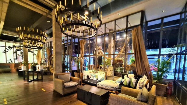 A modern interior with a wooden floor, a large window with curtains, a hanging chair, and a sofa with cushions. - M Boutique Station 18 (Ipoh)
