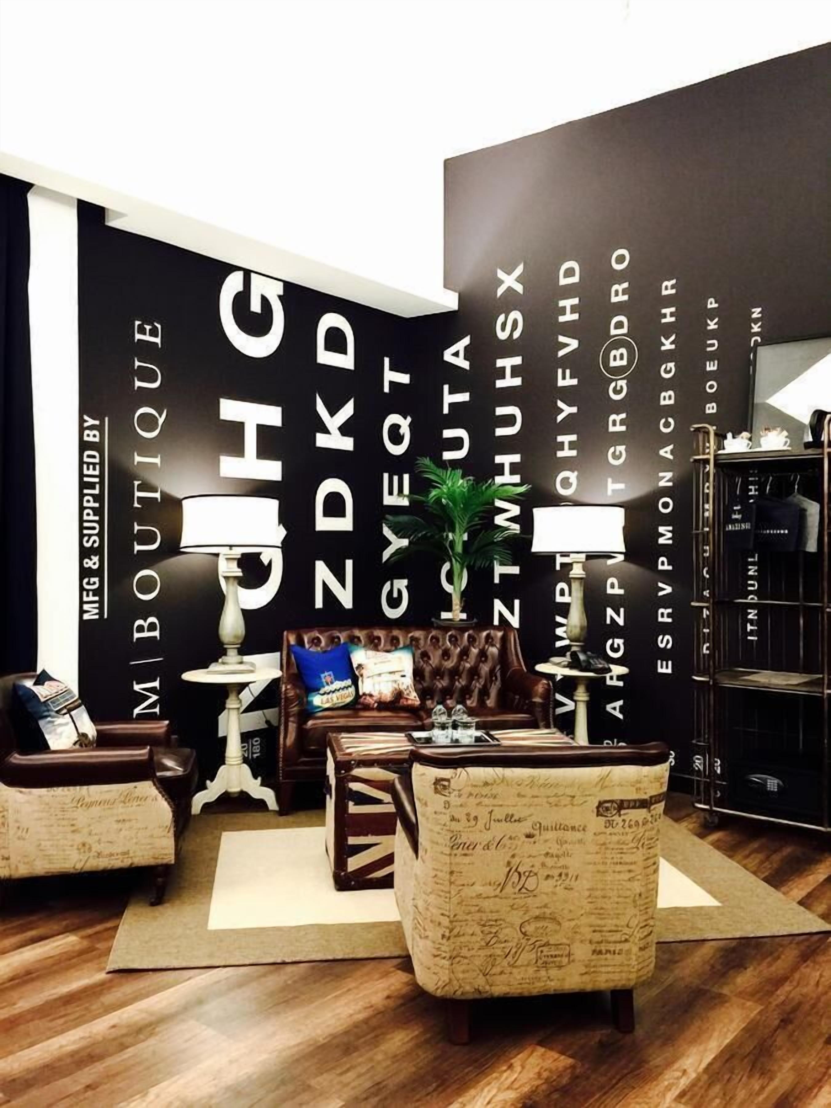 A modern boutique hotel interior with a dark-themed wall, leather furniture, and a vintage-style armchair.