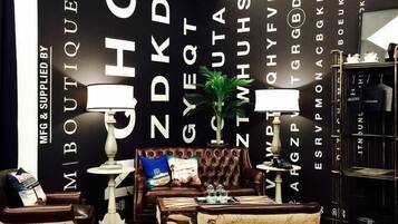 A modern boutique hotel interior with a dark-themed wall, leather furniture, and a vintage-style armchair.