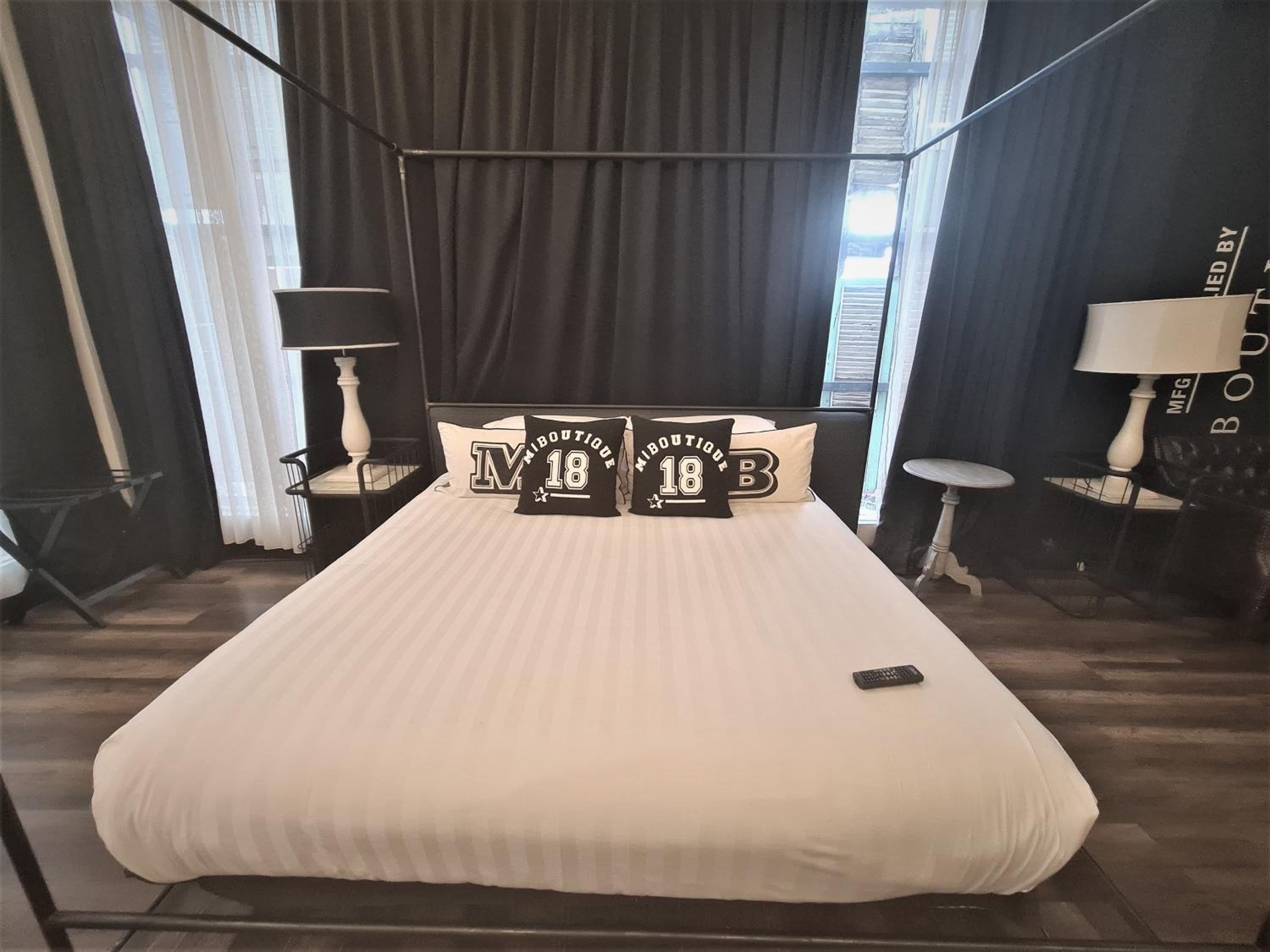 A hotel room with a large bed, two bedside tables, a lamp, and a view of the city through the window.