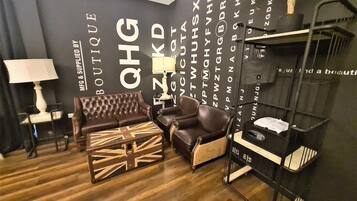 A modern living room with a dark wall, a brown leather sofa, a matching armchair, and a small table with a lamp.