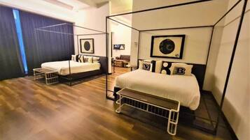 A modern hotel room with a four-poster bed, a small bedside table, and a large window with curtains.