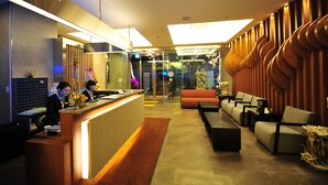 Zona de recepción de un hotel con mostrador, área de estar y diseño interior moderno.
