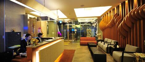 A hotel reception area with a reception desk, seating area, and a modern interior design.