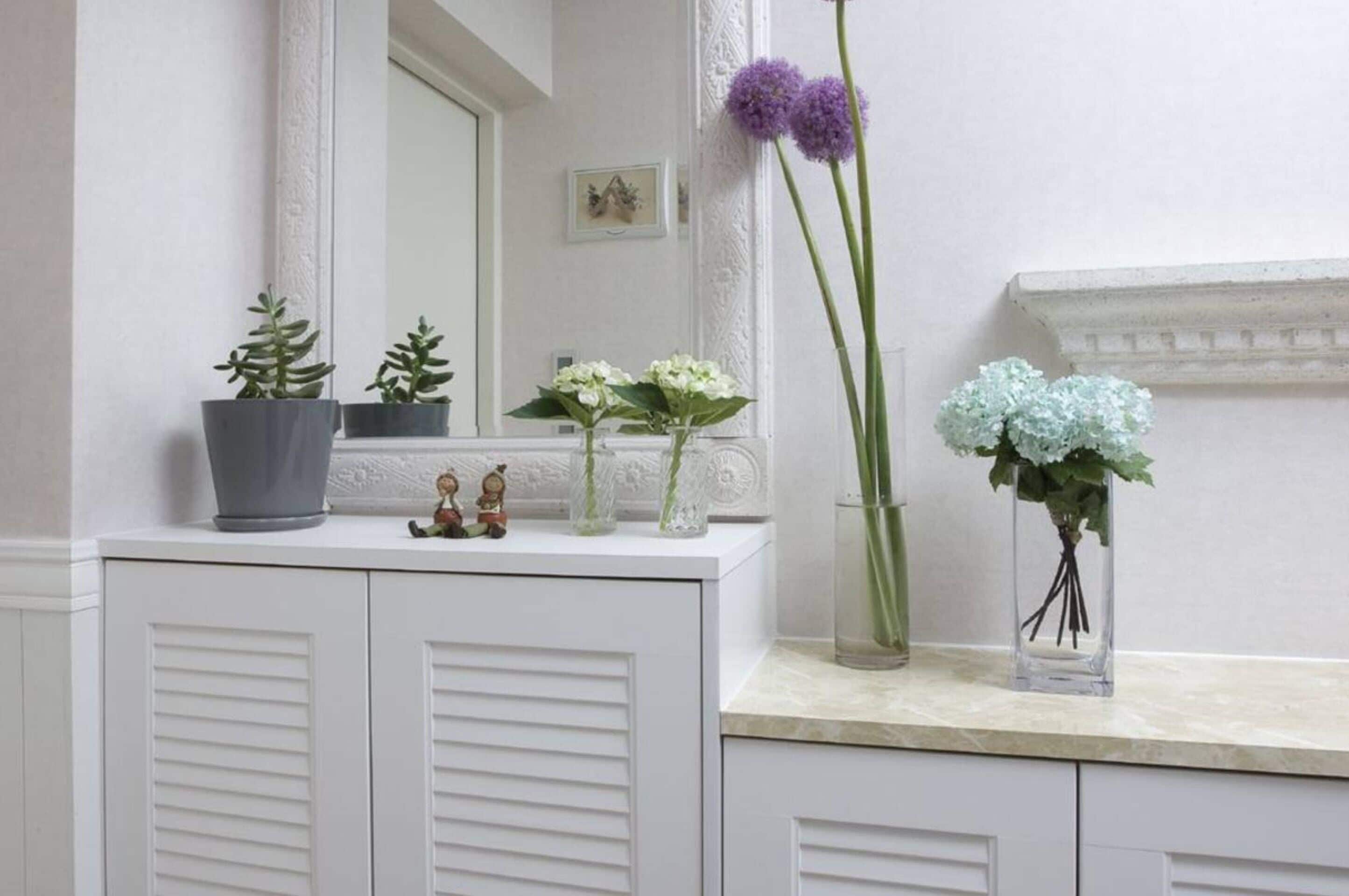 Ein Badezimmer-Waschtisch mit Spiegel, zwei Topfpflanzen und einer Blumenvase.