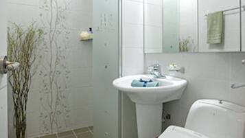 A bathroom with a shower, sink, toilet, and a mirror.