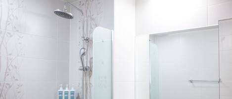 Un baño moderno con cabina de ducha de vidrio, un lavamanos blanco y un espejo sobre él.