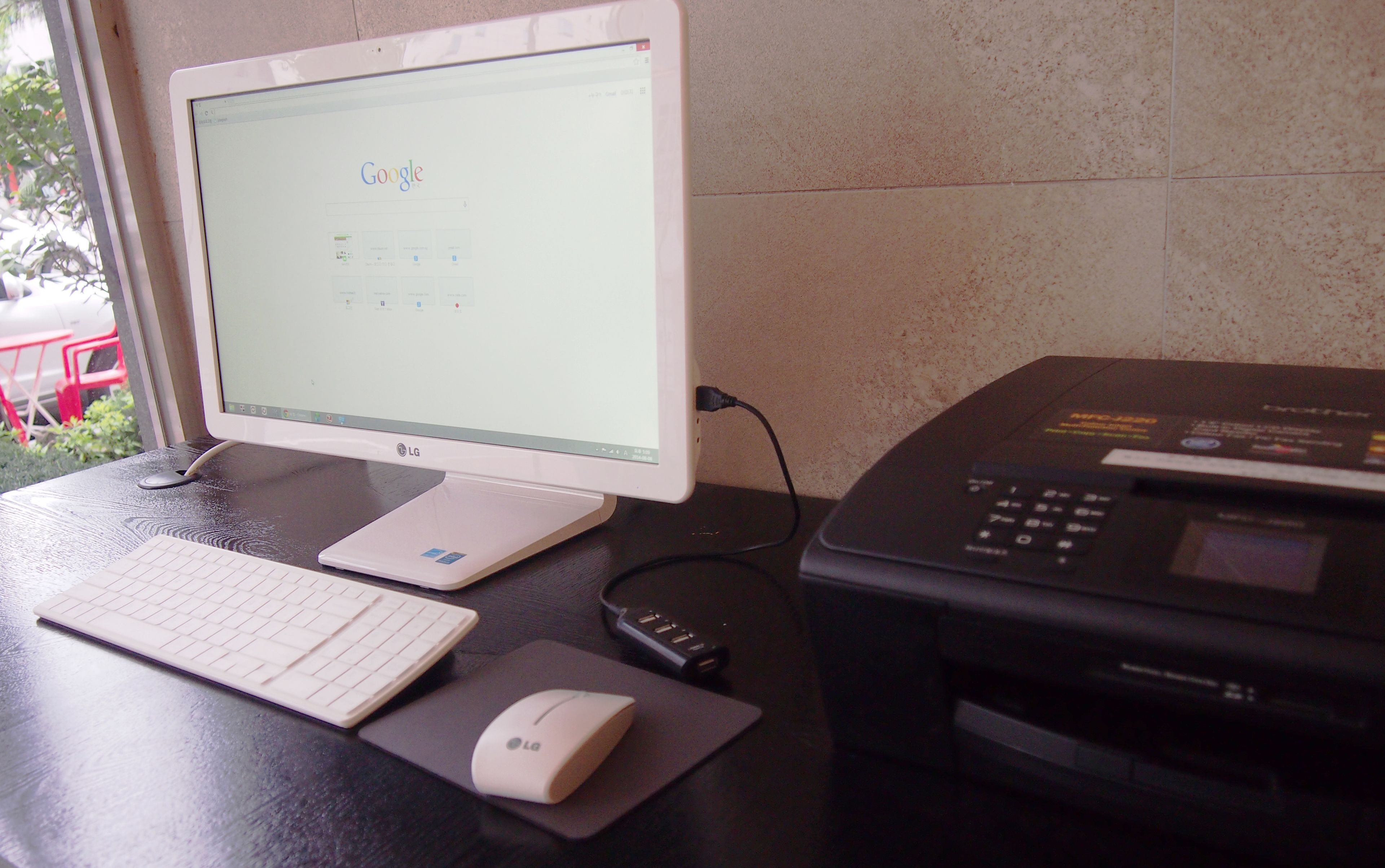 A desktop computer with a monitor, keyboard, mouse, and printer on a desk.