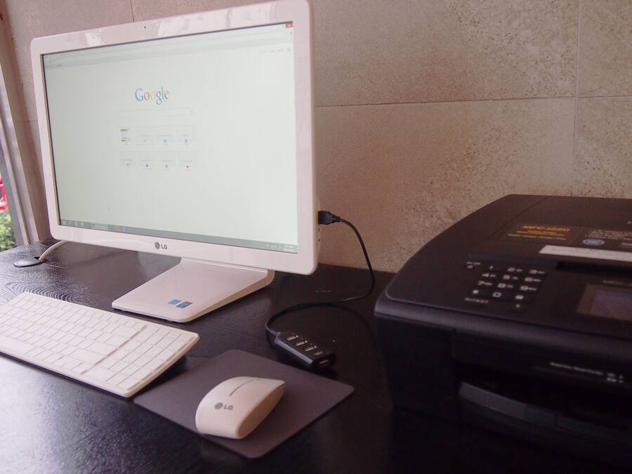 A desktop computer with a monitor, keyboard, mouse, and printer on a desk.