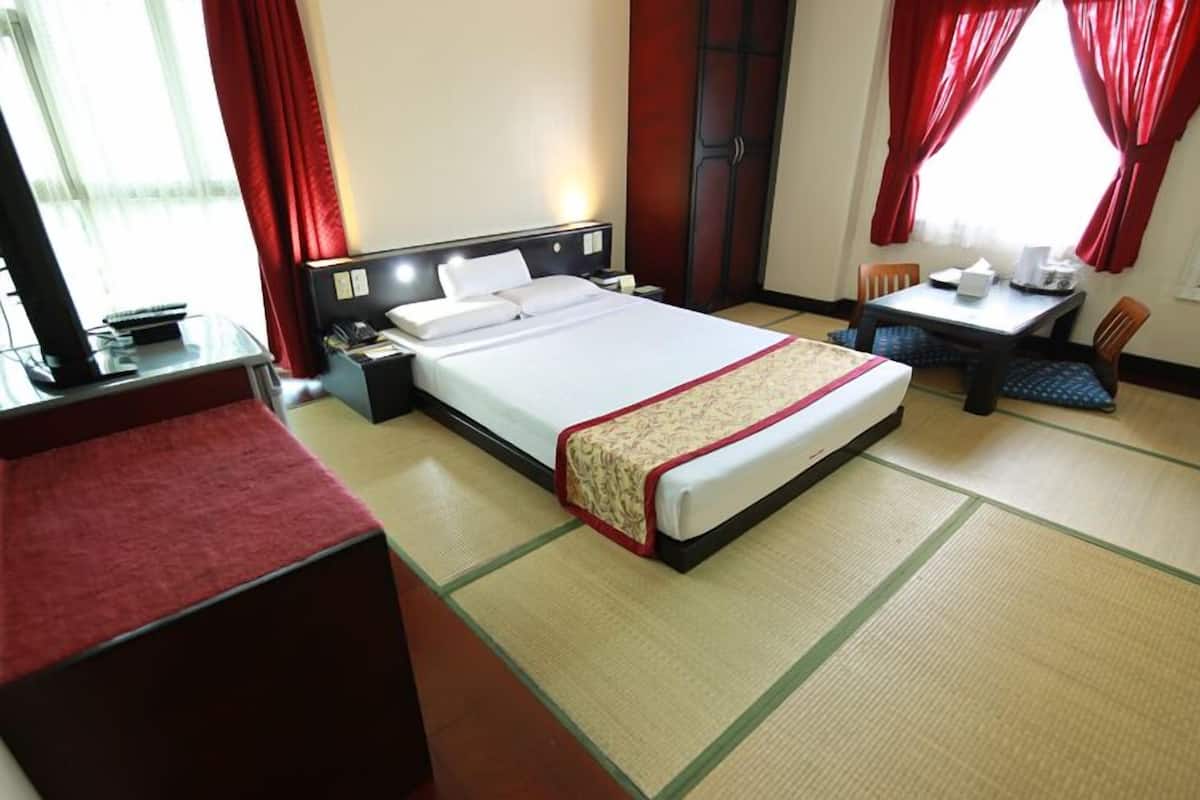 Quarto de hotel com cama, mesa de cabeceira, cadeira e uma pequena mesa com uma cadeira.