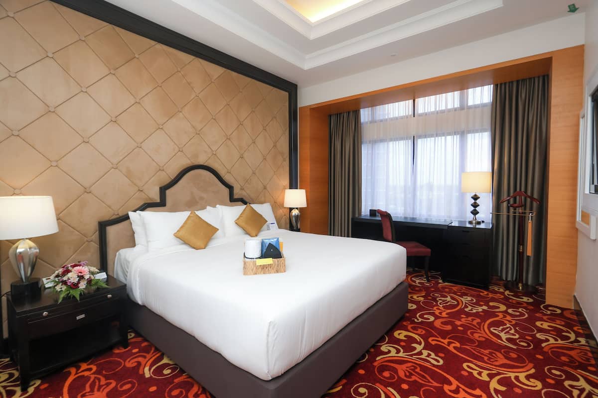 Een hotelkamer met een groot bed, twee nachtkastjes met lampen, een bureau en een stoel.