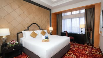 A hotel room with a large bed, two bedside tables with lamps, a desk, and a chair.