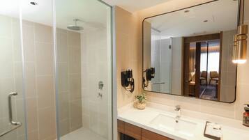 A modern bathroom with a glass shower enclosure, a large mirror, and a dual sink vanity.