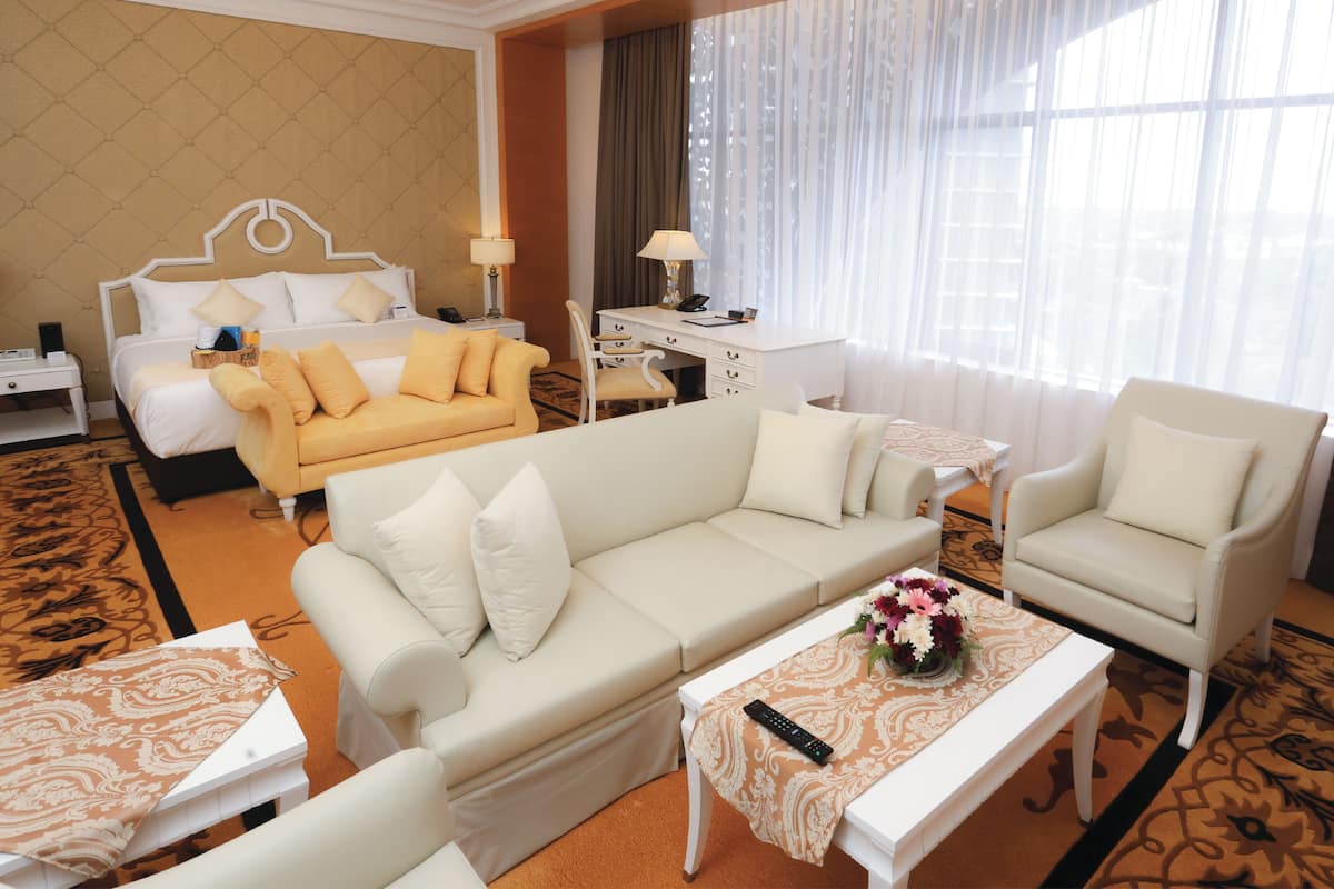 Een hotelkamer met een bed, een slaapbank, een fauteuil, een bureau en een salontafel.