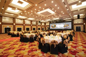 A banquet hall with round tables, black chairs, and gold sashes.