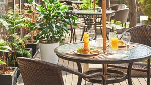 An outdoor patio with round tables, wicker chairs, and potted plants. - Mayplace Seoul (Seoul)