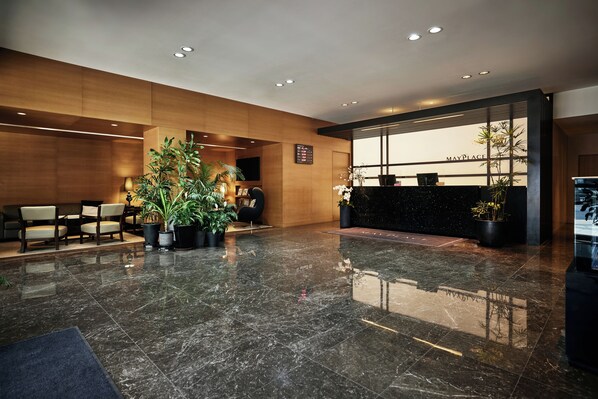 A modern reception area with a black reception desk, seating area with chairs, and potted plants.