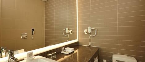 Un baño moderno con un espejo grande, un lavabo y un inodoro.