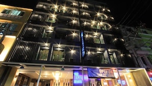 A multi-story hotel with a modern facade, illuminated windows, and a neon sign advertising 'The Crystal Beach'.