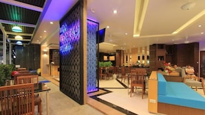 A modern hotel lobby with a reception desk, seating area, and a decorative wall with blue lighting. - The Crystal Beach Hotel (Patong)