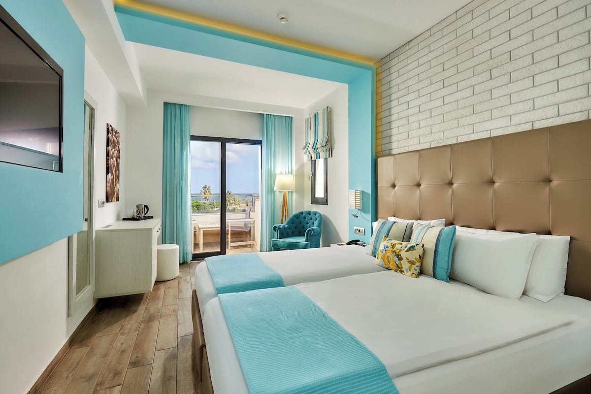 A hotel room with a large bed, a chair, a desk, and a view of the outdoors.