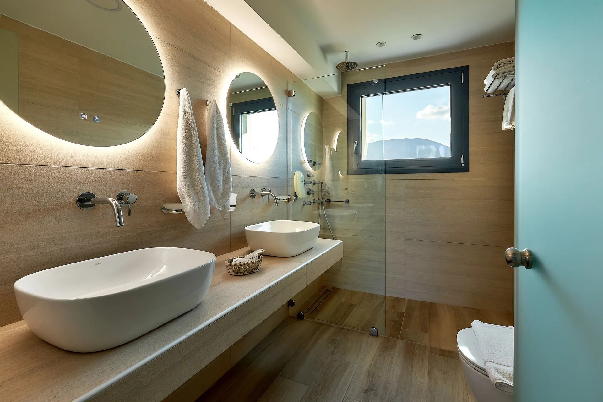 Une salle de bain moderne avec un grand lavabo, un miroir, une douche et une fenêtre.