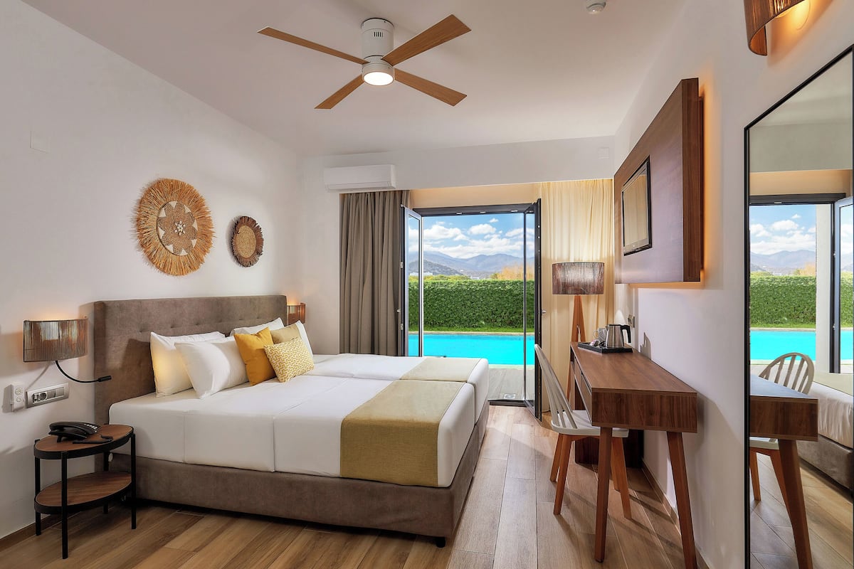 A hotel room with a bed, desk, and a view of a pool.