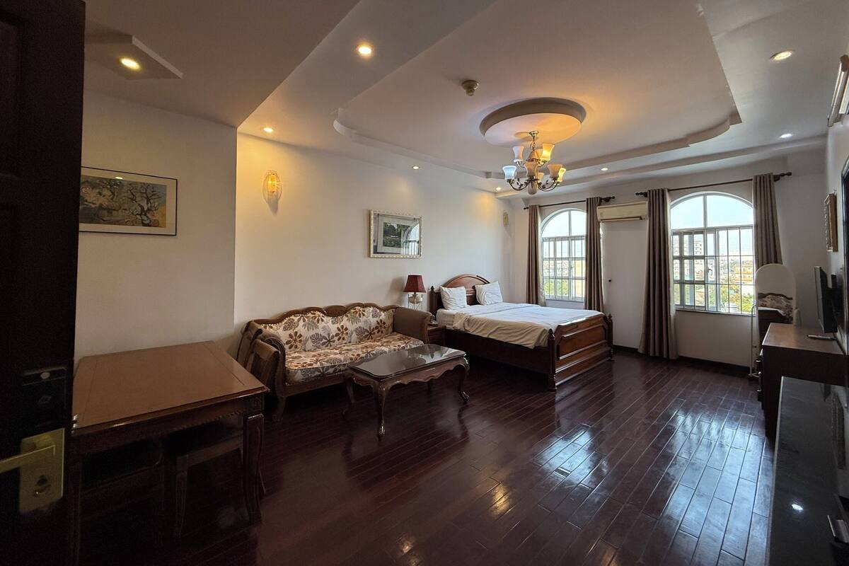 A hotel room with a bed, sofa, and a dining table.