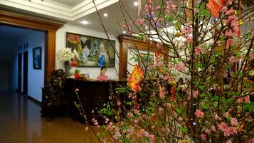 A lobby with a reception desk, a painting, and a decorative tree with pink blossoms.