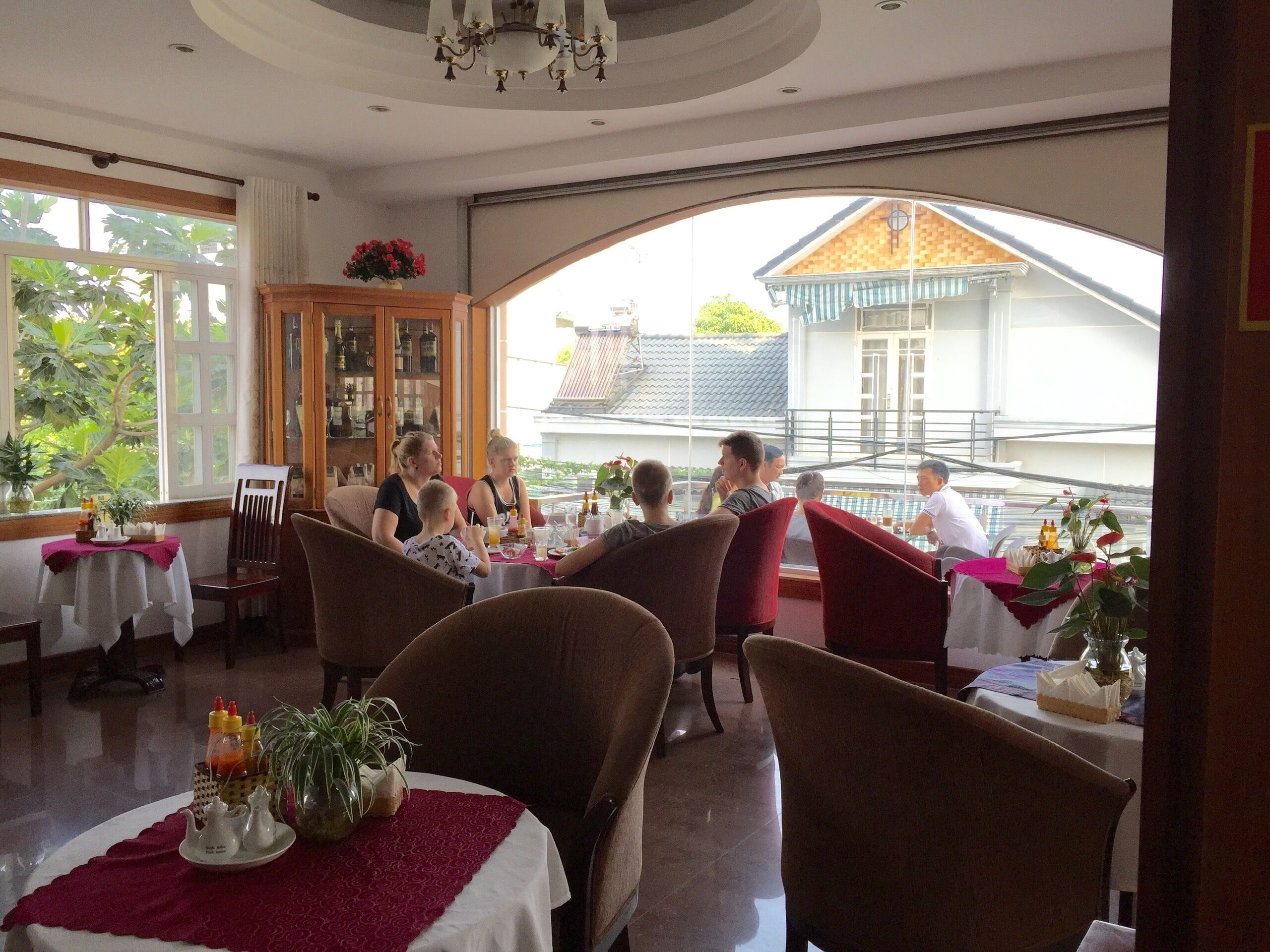 A restaurant with tables and chairs, a view of buildings outside, and a chandelier.