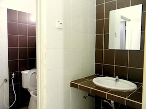 A bathroom with a toilet, sink, and mirror. - Khalifa Inn (Kota Bharu)