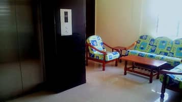 Un vestíbulo con mostrador de recepción, un ascensor, un sofá y una mesa de centro de madera.