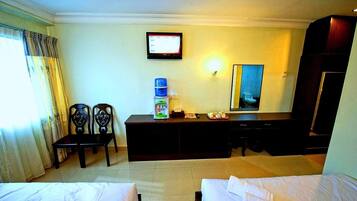 A hotel room with two beds, a desk with a computer monitor, a water dispenser, and a mirror.