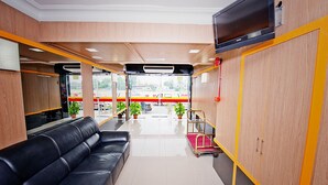 A modern hotel lobby with a black leather sofa, wooden paneling, and a view of the street through large windows. - Hotel Bintang Indah (Kota Bharu)