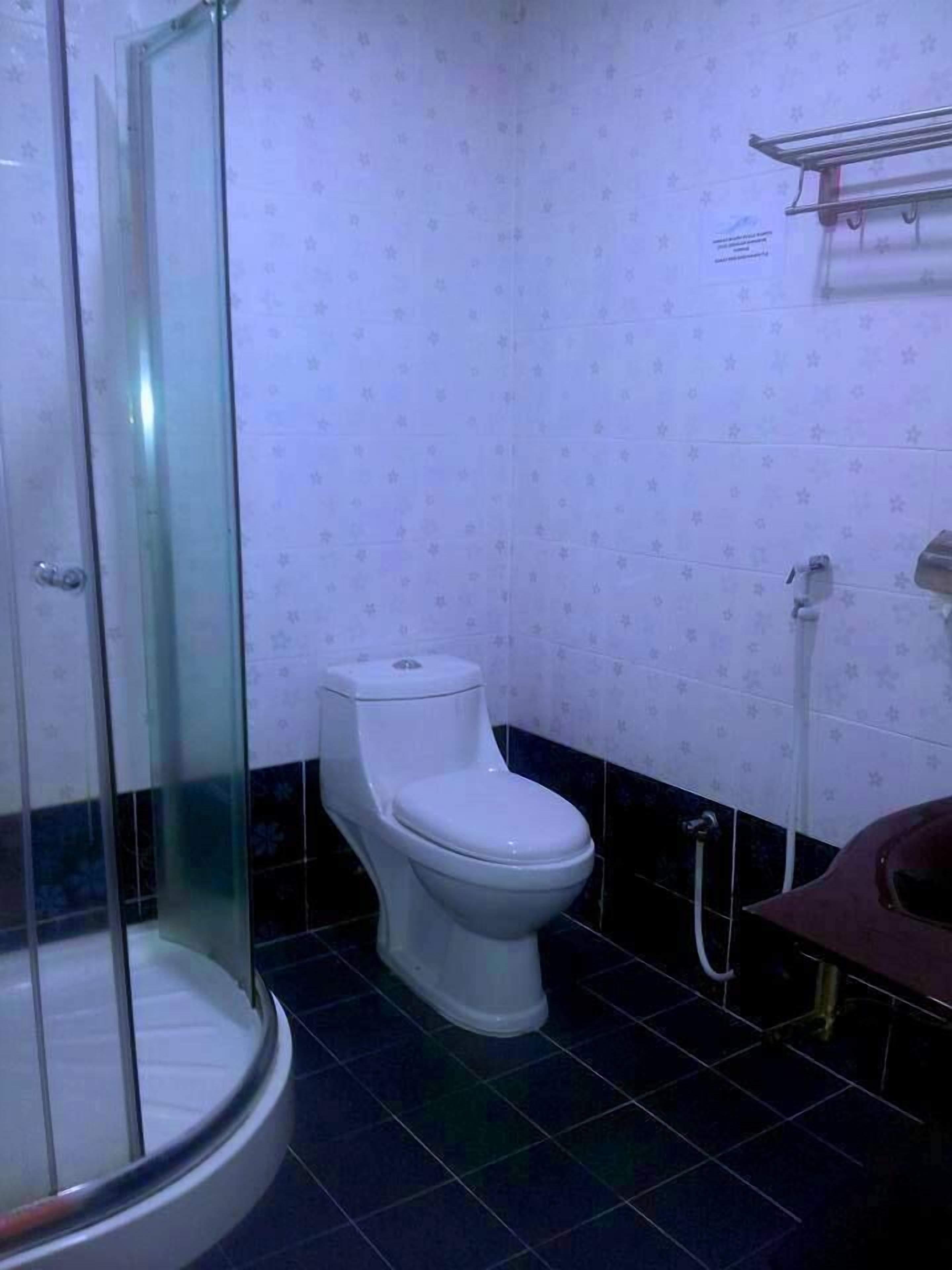 A bathroom with a glass-enclosed shower, a toilet, and a sink.