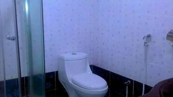 A bathroom with a glass-enclosed shower, a toilet, and a sink.