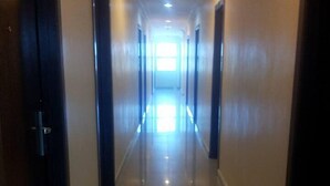 A long, narrow hallway with doors on both sides, leading to a bright room at the end. - Hotel Bintang Indah (Kota Bharu)