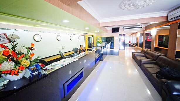 A hotel reception area with a reception desk, a large floral arrangement, and a seating area with leather couches. - Hotel Bintang Indah (Kota Bharu)