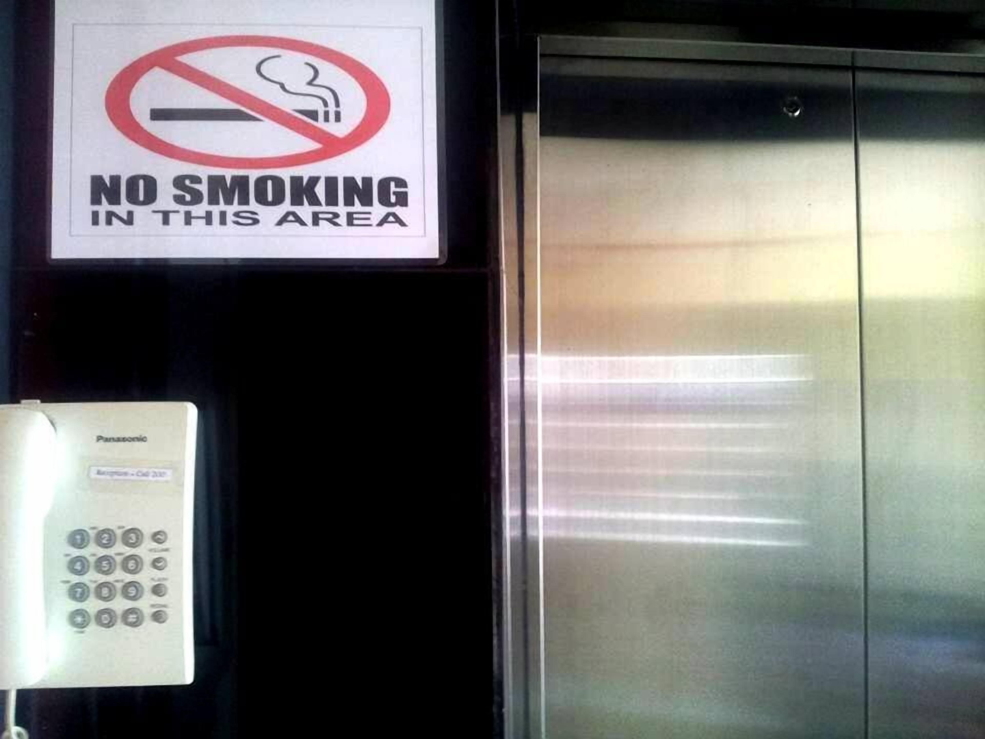 A no smoking sign, an elevator, and a Panasonic phone.