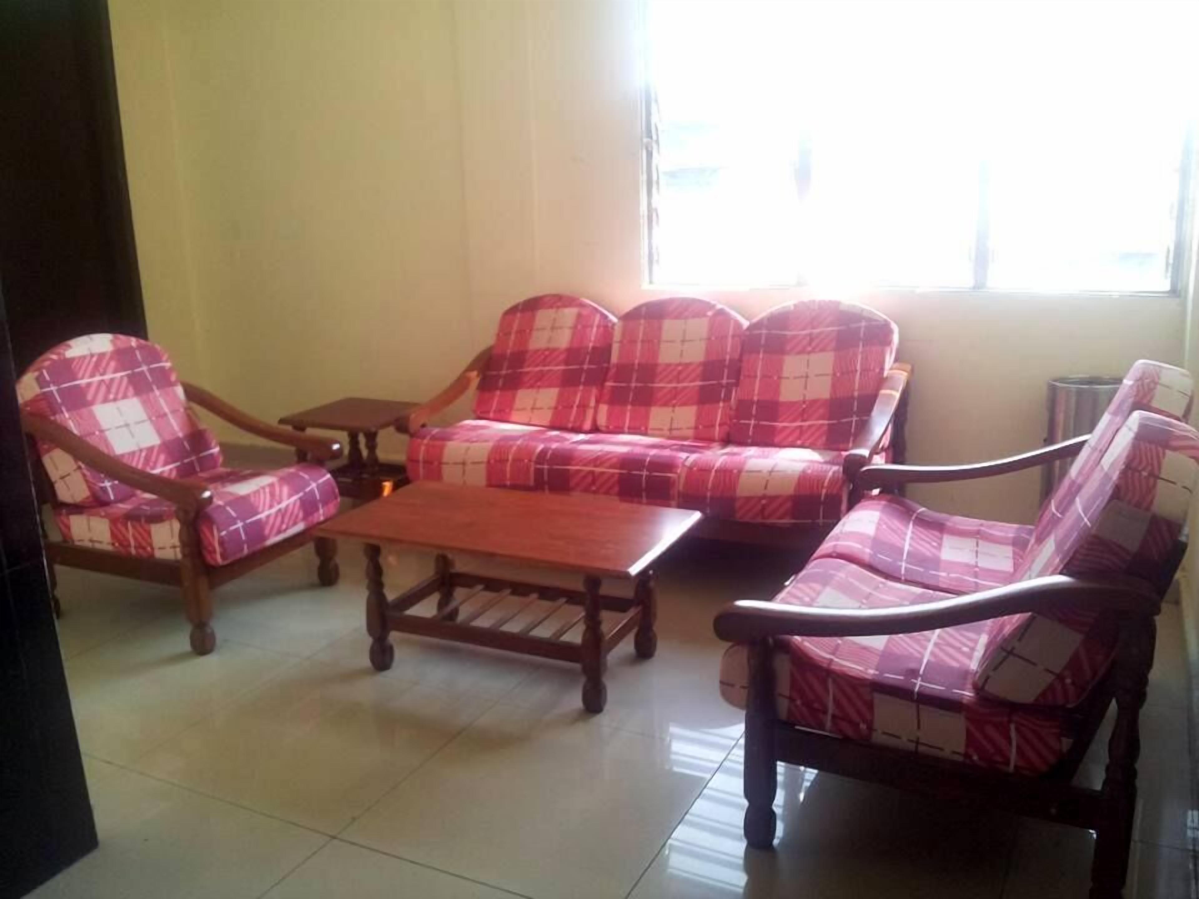 A living room with a sofa set and armchairs, a coffee table, and a radiator.