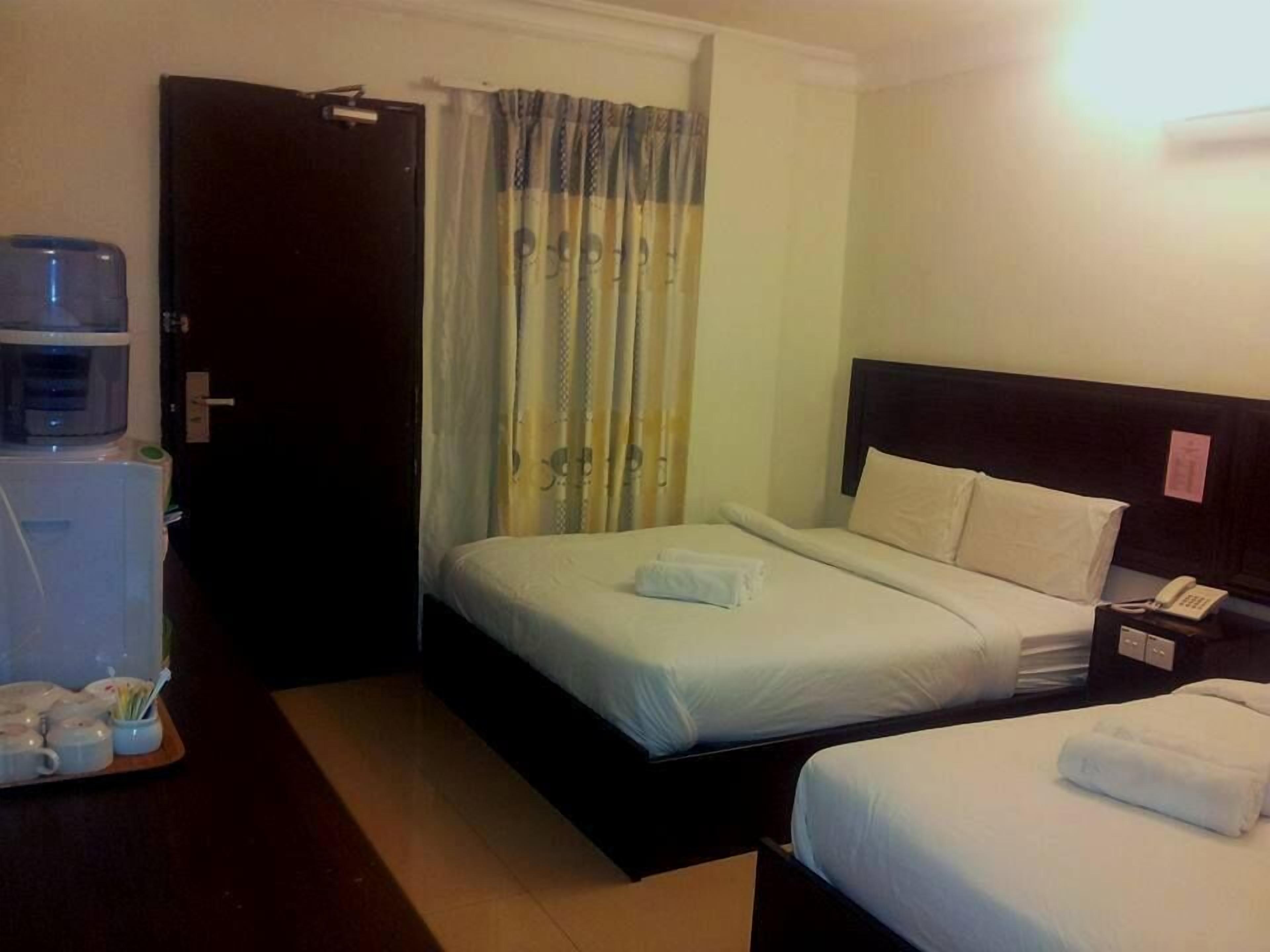 A hotel room with a bed, bedside table, and a water dispenser.