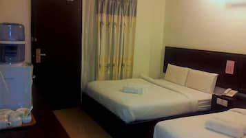 A hotel room with a bed, bedside table, and a water dispenser.